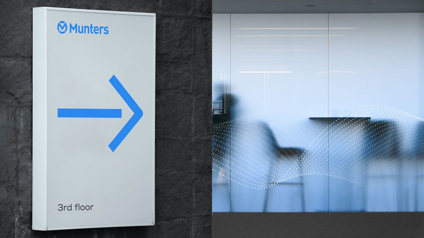 A blue sign with an arrow pointing to a glass door.