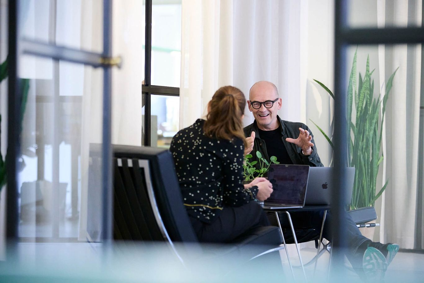 A man and woman sitting in an office talking to each other.