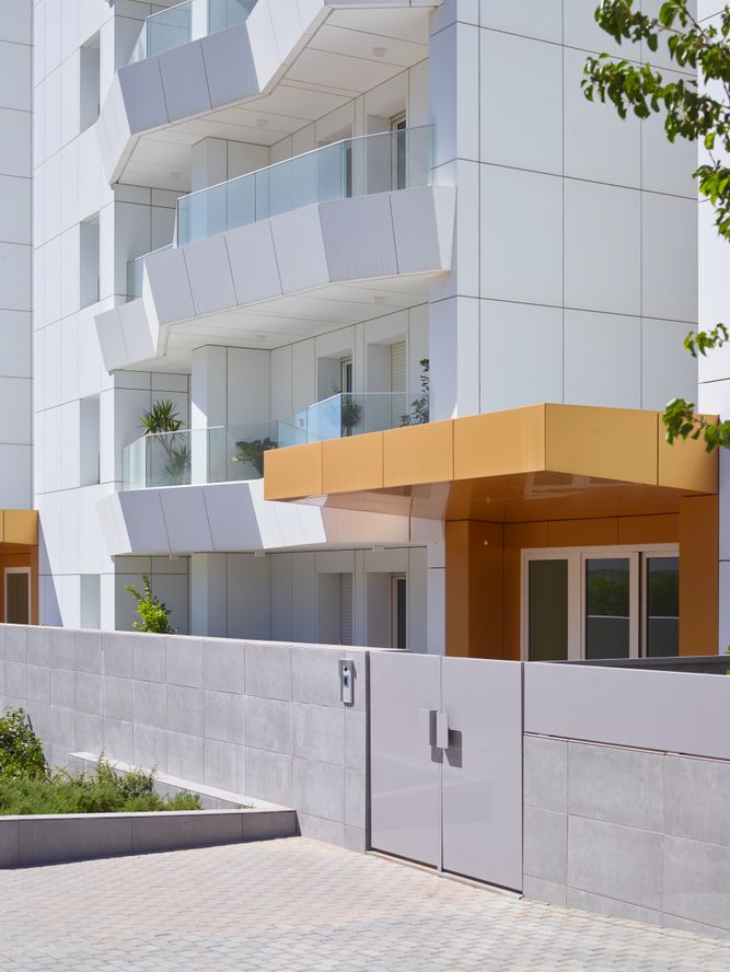 A white apartment building with a yellow gate.