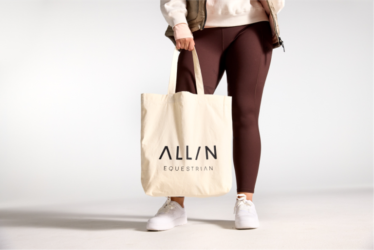 A woman holding a tote bag with the word alun on it.