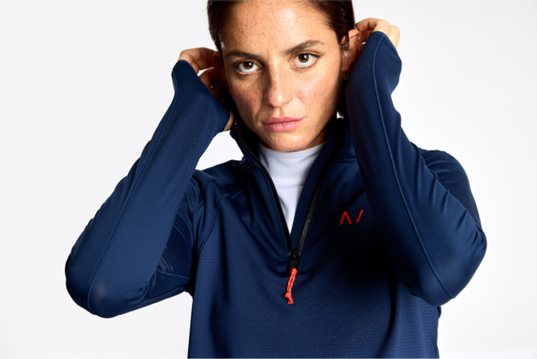 A woman is posing for a photo in a blue sweatshirt.