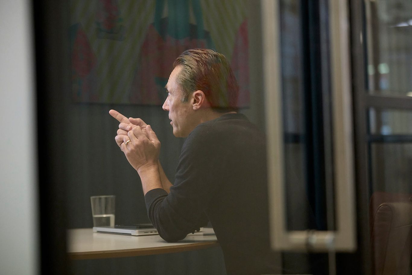 A man sitting at a desk looking out of a window.