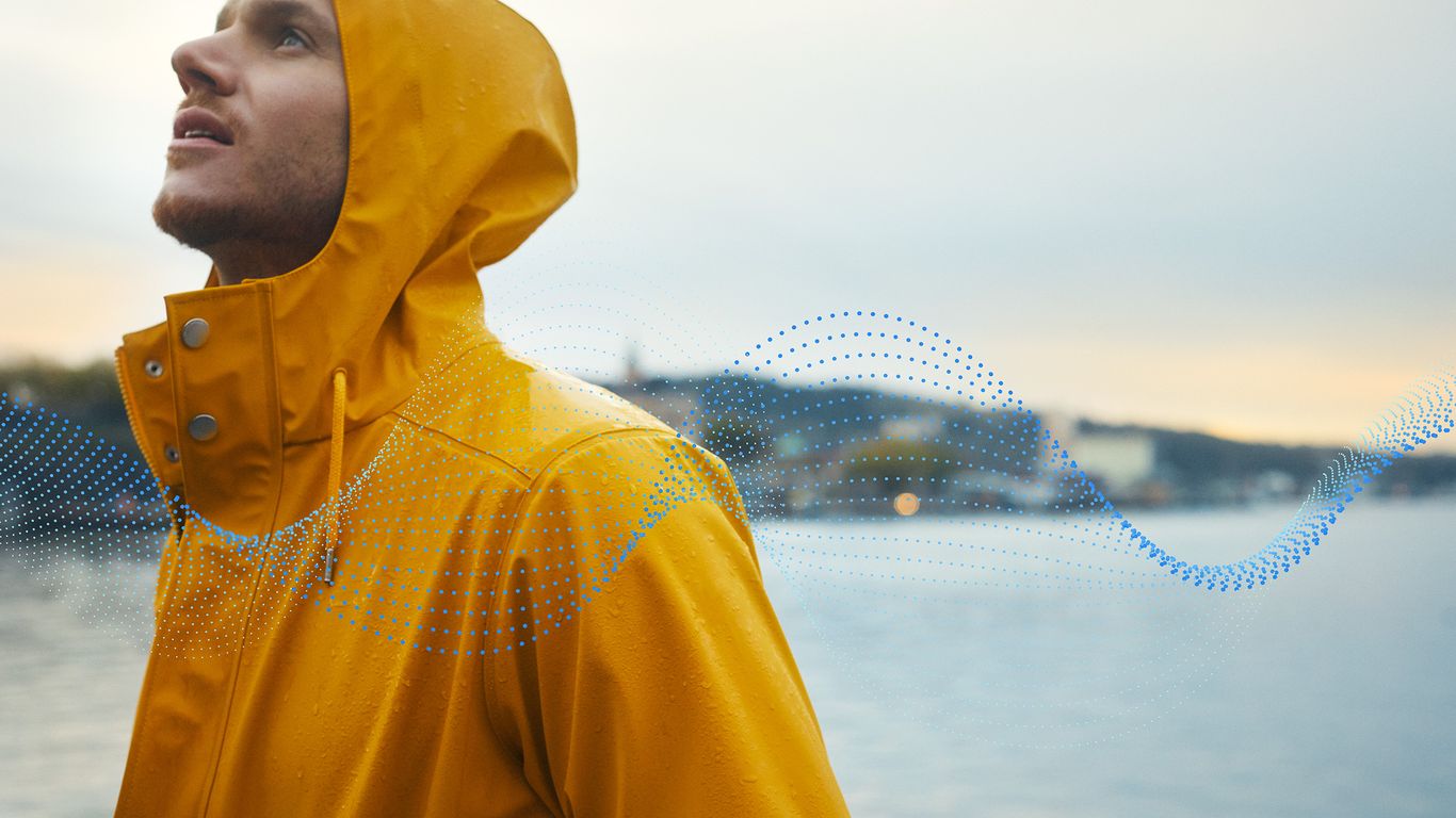 A man in a yellow raincoat standing next to a body of water.