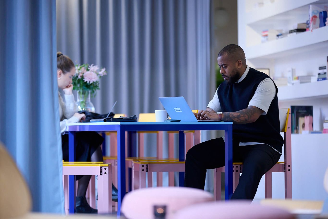 Two people sitting at a table working on their laptops.