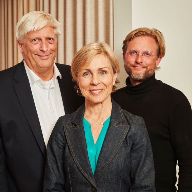 Three people posing for a picture in an office.